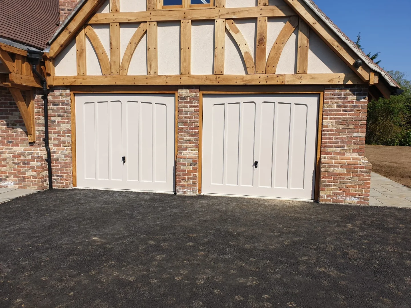 White side-hinged garage doors on a traditional Tudor-style home