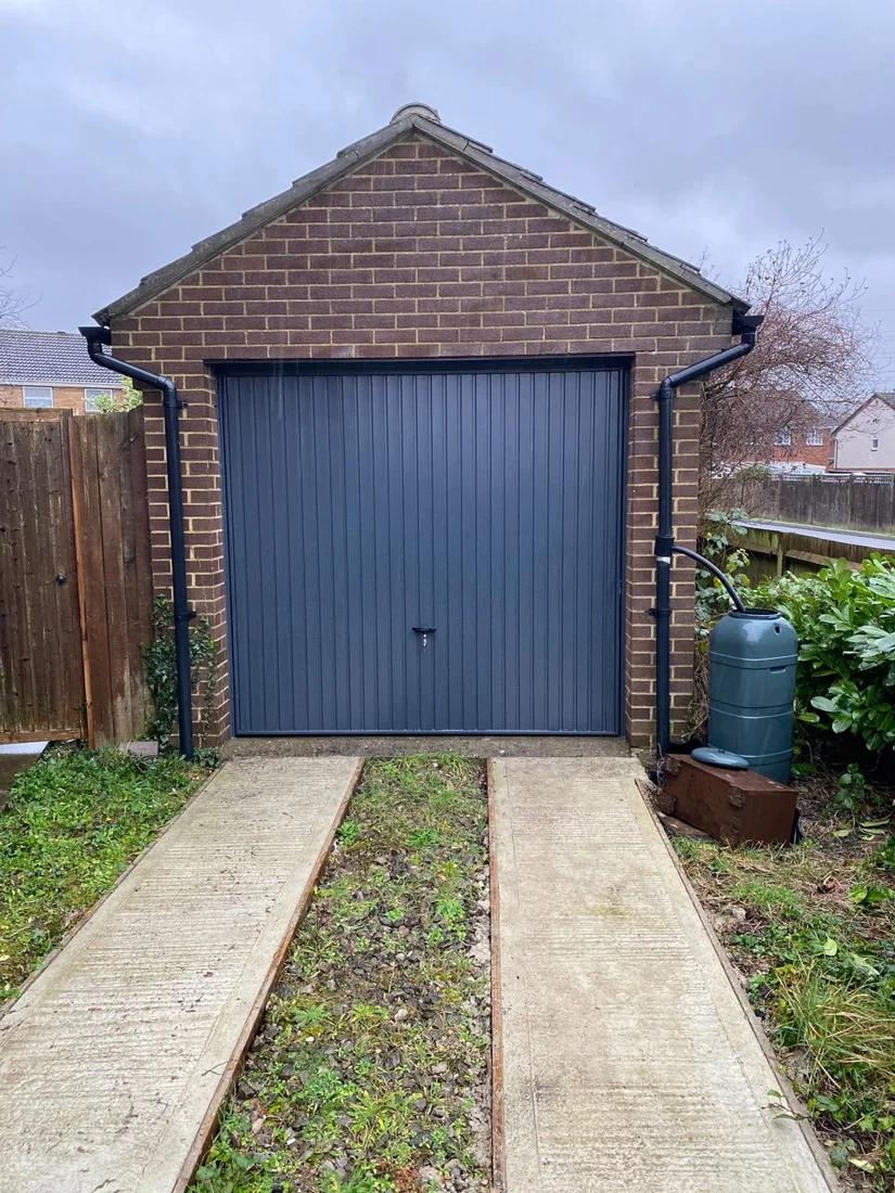 Blue traditional up-and-over garage door fitted to a detached garage